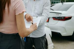 Kunden und Auto Versicherung Agenten haben trat ein in Vereinbarungen und unterzeichnet Unterlagen zu Anspruch Vergütung nach auf das Straße im Sonne Licht foto