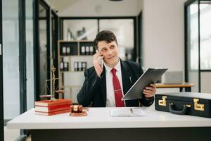 Gerechtigkeit und Gesetz Konzept. männlich Richter im ein Gerichtssaal das Hammer, Arbeiten mit Clever Telefon und Laptop und Digital Tablette Computer auf Holz Tabelle foto