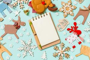 Draufsicht auf Notizbuch auf blauem Hintergrund aus Weihnachtsdekorationen und Spielzeug. Weihnachtsschmuck-Konzept foto