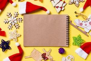 Draufsicht des Notebooks mit Weihnachtsschmuck und Weihnachtsmützen auf gelbem Hintergrund. fröhliches Urlaubskonzept foto