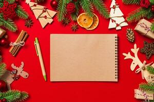 Draufsicht des Notebooks auf rotem Hintergrund aus Weihnachtsschmuck. neujahrszeitkonzept foto