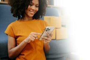 jung Frau halten ein Smartphone, Tablette zeigen Zahlung Erfolg mit Gelb Paket Box wie online Einkaufen Konzept foto