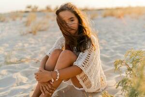 klein Mädchen im stilvoll Boho Sommer- Outfit posieren auf das Strand. warm Sonnenuntergang Farben. wacation und Reise Konzept. foto