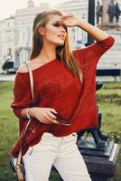 Straße Porträt von ein jung schön elegant Frau im rot Pullover. foto