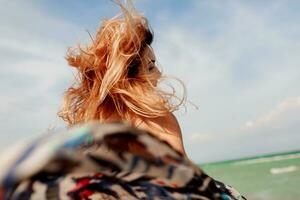 sorglos Frau Springen Freiheit auf Weiß Sand. Blau Ozean Hintergrund. windig Haare. foto