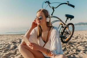 jung attraktiv blond lächelnd Frau auf Ferien Sitzung auf Strand foto