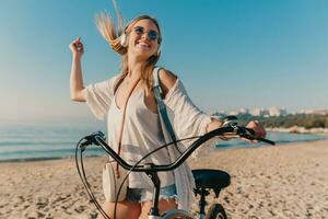 jung attraktiv blond lächelnd Frau Gehen auf Strand mit Fahrrad foto