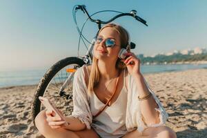 jung attraktiv blond lächelnd Frau auf Ferien Sitzung auf Strand foto