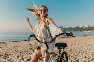 jung attraktiv blond lächelnd Frau Gehen auf Strand mit Fahrrad foto