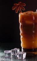 kaltes Kaffeegetränk oder Cocktail mit Eis auf dunklem Hintergrund foto