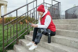 Frau, die nach einer Beinoperation eine Knieorthese oder Orthese trägt und im Park spazieren geht foto