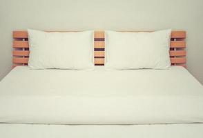 weiße Decken und Kissen auf dem Holzbett im Schlafzimmer foto