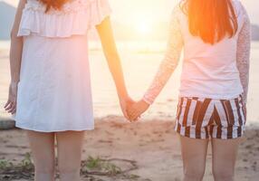 Zwei junge Frauen halten sich am Meer an den Händen foto