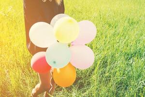 glückliche junge schöne Frau und bunte Luftballons im Grünland. foto