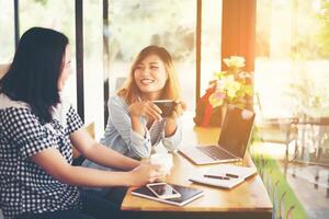 Zwei junge schöne Frauen unterhalten sich in einem Café foto