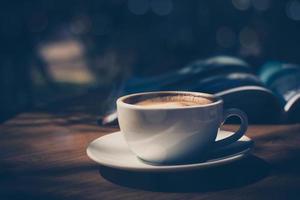 Tasse Kaffee mit Zeitschrift auf dem Tisch im Café in dunklem Ton und Vintage foto