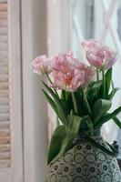 Weich fokussierter Strauß rosa Tulpen in einer großen alten Vase auf einem Fensterbrett foto