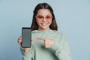 hübsches Teenager-Mädchen, das ein Smartphone in den Händen hält foto