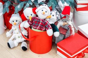 lustige Spielzeug-Schneemänner und Geschenke unter geschmücktem Tannenbaum foto
