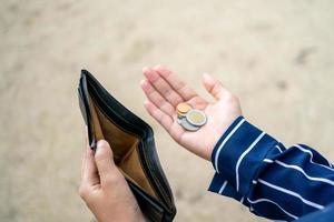 Frau hält einen leeren Geldbeutel und Münzen in der Hand. foto