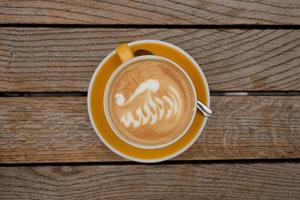 Draufsicht auf eine Tasse Cappuccino mit Latte Art am Holztisch foto