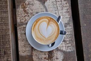 Draufsicht auf eine Tasse Cappuccino mit Herzschaum auf einer Holzoberfläche foto
