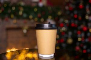 ein Einweg Kaffee Tasse mit ein Deckel auf das Hintergrund von ein Weihnachten Baum. Platz zum Werbung foto