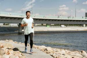 ein Trainer mit Brille tut ein Laufen Übung jeder Tag, ein gesund Lebensstil. ein sportlich Person Verwendet ein Fitness Uhr und ein Laufen App. ein Mann Ausbildung Fitness im ein komfortabel T-Shirt. foto