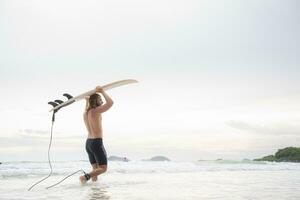 Surfer Mann mit seine Surfbrett auf das Strand. foto