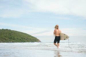 Surfer Mann mit seine Surfbrett auf das Strand. foto