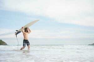 Surfer Mann mit seine Surfbrett auf das Strand. foto