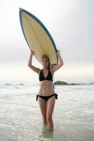 Surfer Mädchen mit ihr Surfbrett auf das Strand. foto