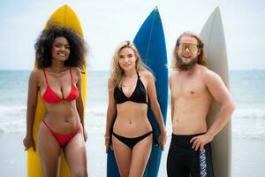 Gruppe von freunde im Badeanzüge posieren mit Surfbretter auf das Strand. foto