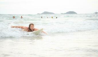 jung Mann Surfen auf das Strand haben Spaß und balancieren auf das Surfbrett foto