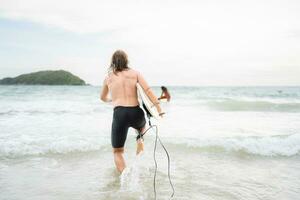 jung Mann Surfen auf das Strand haben Spaß und balancieren auf das Surfbrett foto