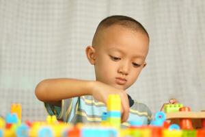 asiatisch Junge spielen mit lehrreich Spielzeuge Dort sind viele schön Farben auf das Tabelle im das Haus. foto
