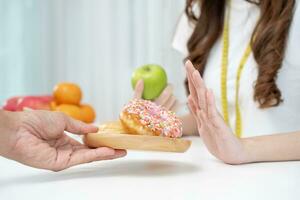 Ernährung und Diät. schönheit schlank weiblicher körper verwirren donut. frau in trainingskleidung erreicht gewichtsverlustziel für ein gesundes leben, verrückt nach dünnheit, dünner taille, ernährungsberaterin. foto