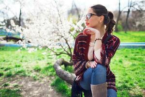 sonnig Frühling Porträt von glücklich jung Frau Lachen und posieren in der Nähe von Blume Baum. foto