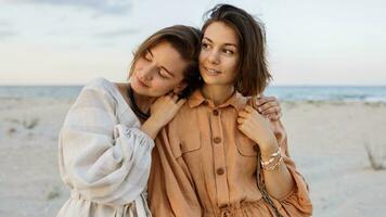 Sommer- Mode Bild von zwei Brünette europäisch Frauen im Leinen- Kleider posieren auf das Strand foto