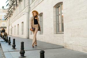 atemberaubend blond Frau im beiläufig Leder passen Gehen auf das Straße im Paris. draussen Mode Stil. Beige Hut und Geldbörse . voll Länge. foto