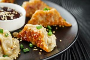 köstlich gebraten Gyoza Knödel auf ein schwarz Teller foto