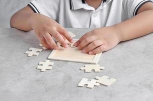 asiatischer kleiner Junge, der hölzernes Puzzlespiel spielt foto