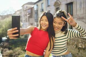 positiv asiatisch weiblich Touristen Schießen Selfie auf Handy foto