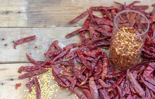 getrocknete Peperoni auf Holztisch und Chiliflocken im Glas, Gewürz foto