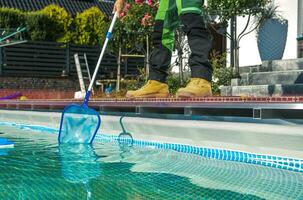 am Pool Instandhaltung Arbeiter Reinigung Wasser Oberfläche mit ein Netz foto