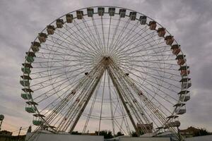 ein Ferris Rad ist gezeigt im Vorderseite von ein wolkig Himmel foto