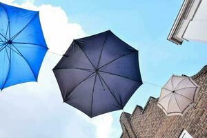 drei Regenschirme hängend von ein Gebäude foto