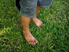 ein wenig Junge asiatisch Junge Stehen auf das Gras barfuß foto