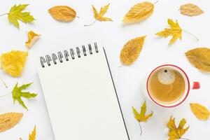 spotten hoch. öffnen Skizzenblock oder Notizbuch auf Künstler Schreibtisch Arbeitsplatz, Kaffee und Gelb Herbst Blätter auf Weiß Hintergrund. kreativ Konzept, leeren Buchseite. oben Sicht, Kopieren Raum foto