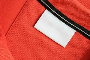 leer Weiß Wäsche Pflege Kleider Etikette auf Orange Hemd Stoff Textur Hintergrund foto